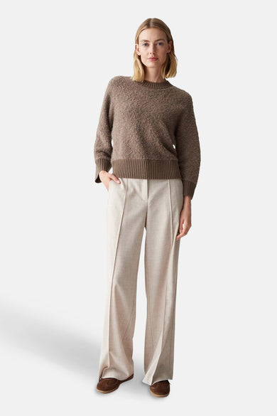 Pull à col rond brun de OPUS, porté avec un pantalon beige à coupe droite et des chaussures marron.

