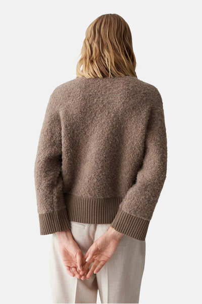 Pull à col rond marron de OPUS, texture bouclée, manches longues, dos visible, porté avec un pantalon beige.
