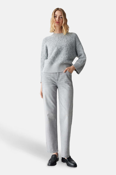 Pull à col rond gris par OPUS, avec une texture bouclée, porté avec un jean et des chaussures noires.
