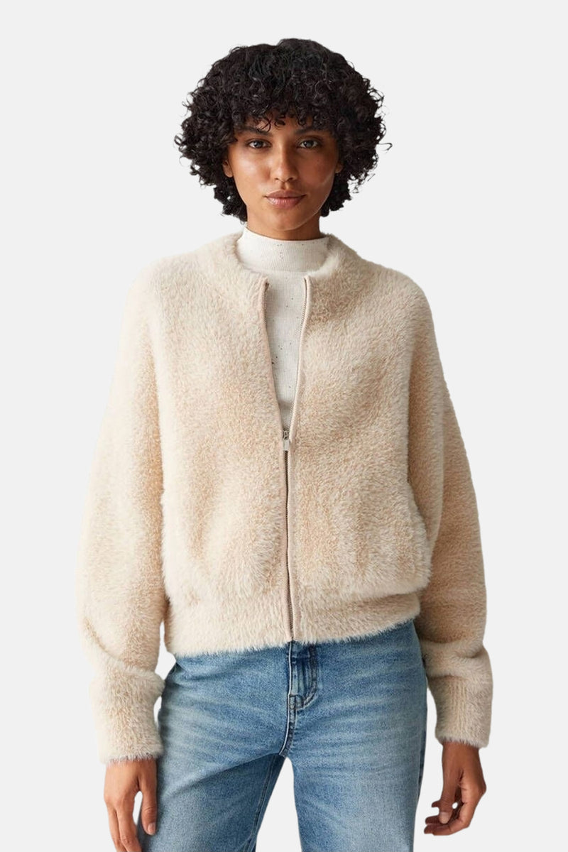Cardigan beige duveteux par OPUS, porté sur un col roulé blanc et un jean bleu clair.