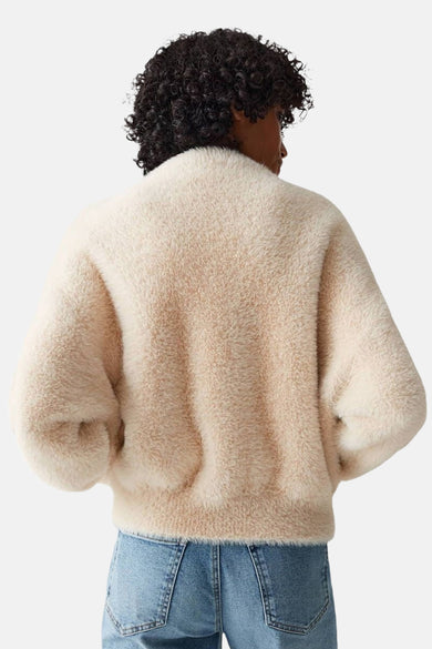 Cardigan beige en fausse fourrure de OPUS, porté avec un jean bleu, vue de dos.
