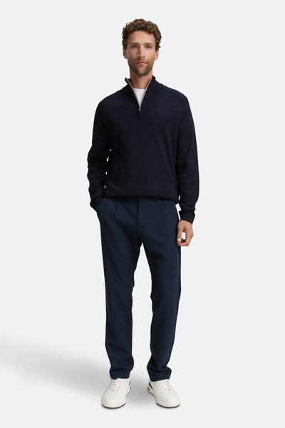 Pull bleu à col rond de Tom Tailor, porté avec un pantalon marine plissé et des baskets blanches.