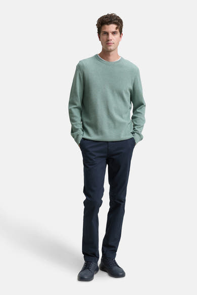 Groene trui met ronde hals van Tom Tailor, gedragen met een marineblauwe broek en bijpassende sportschoenen.