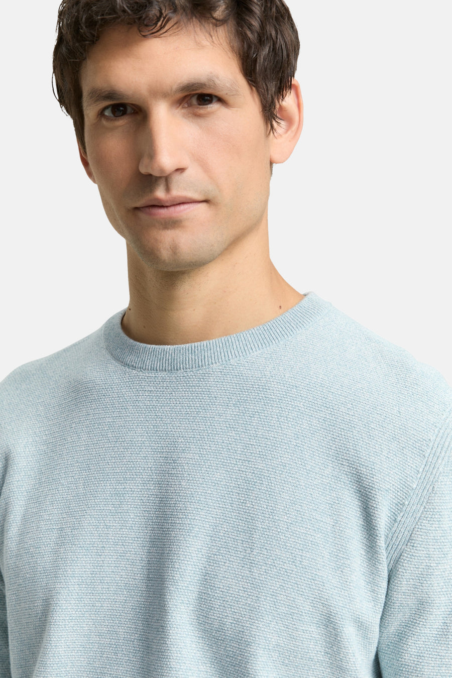 Ronde hals trui blauw van Tom Tailor, in een getextureerd breisel, gedragen door een man.