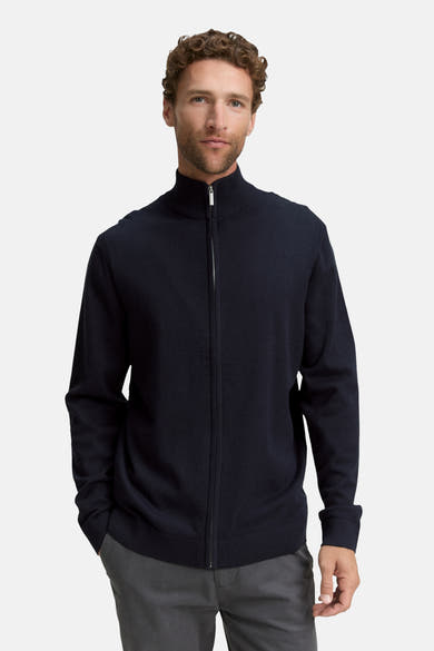 Gilet bleu de Tom Tailor, avec fermeture éclair argentée et porté sur un pantalon gris uni.