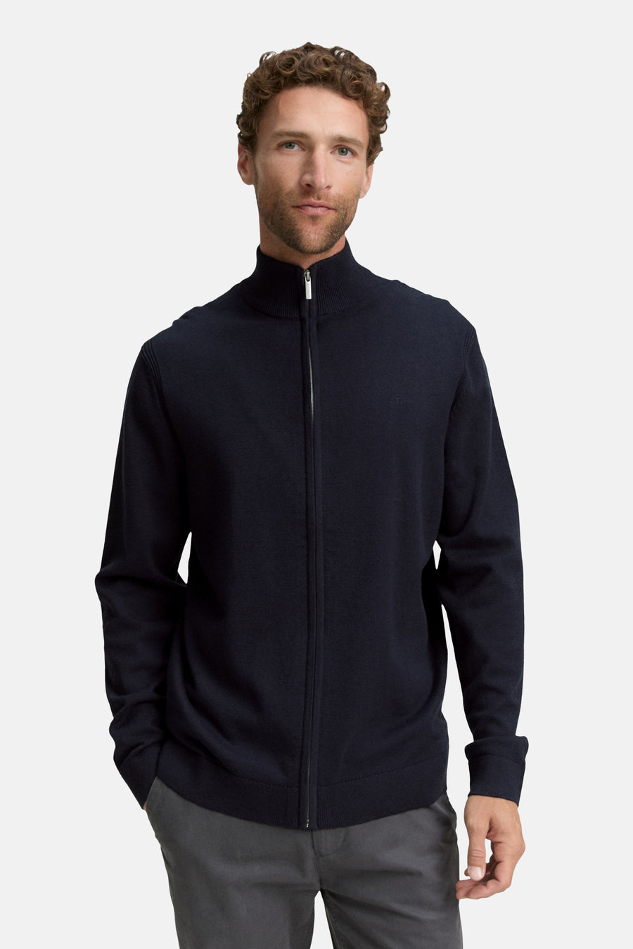 Gilet bleu de Tom Tailor, avec fermeture éclair argentée et porté sur un pantalon gris uni.