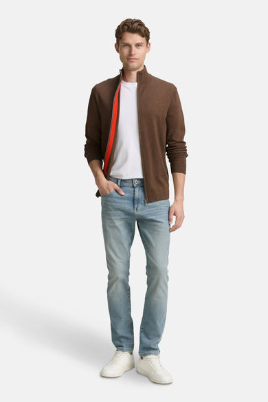 Bruine Tom Tailor gilet, gedragen over een wit T-shirt en een lichtblauwe jeans met witte sneakers.