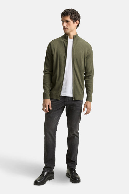 Gilet kaki par Tom Tailor, porté avec un t-shirt blanc et un jean noir, chaussures noires à lacets.
