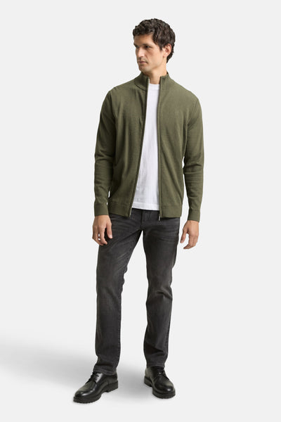 Gilet kaki par Tom Tailor, porté avec un t-shirt blanc et un jean noir, chaussures noires à lacets.
