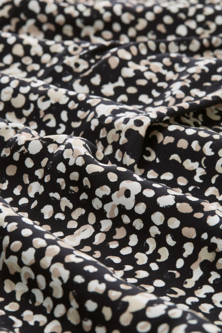 Chemisier 3/4 noir de Tom Tailor avec un motif à pois beige sur un tissu texturé.
