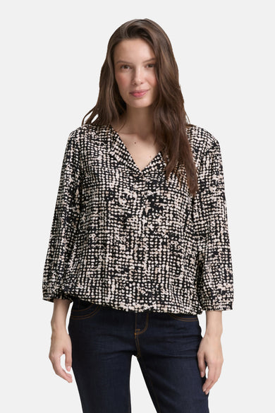 Blouse noire 3/4 de Tom Tailor, à motif géométrique all-over, portée avec un jean foncé.