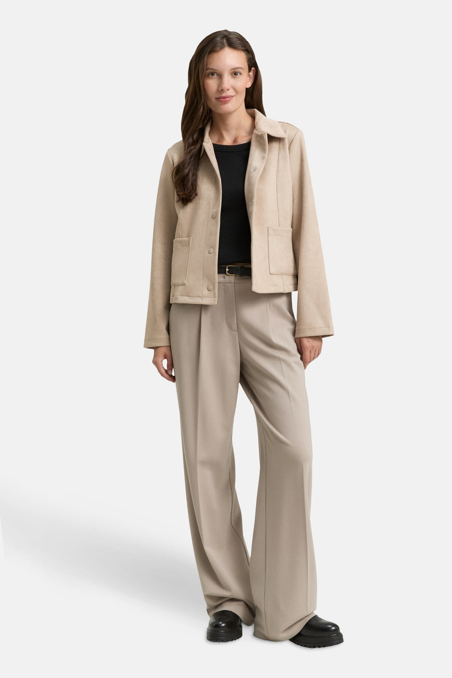 Veste courte beige Tom Tailor, avec poches plaquées et boutons, portée avec un pantalon beige et un haut noir.
