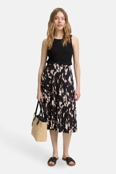 Lange meerkleurige rok van Tom Tailor, met abstract patroon, gedragen met een zwarte tanktop en een rieten tas.