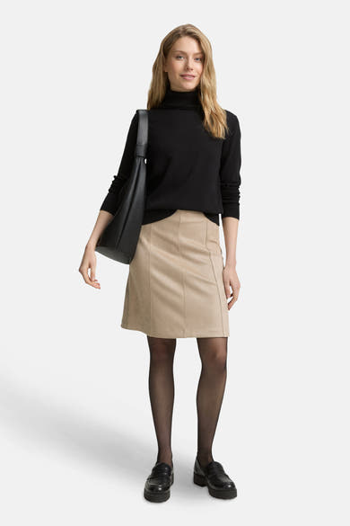 Korte beige rok van Tom Tailor, met verticale naden, gedragen met een zwarte trui, panty en zwarte schoenen.