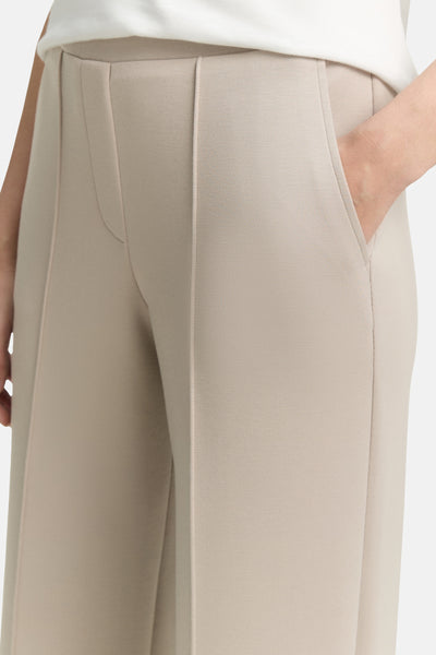 Jogging beige de Tom Tailor, avec une main dans la poche, coupe cropped.
