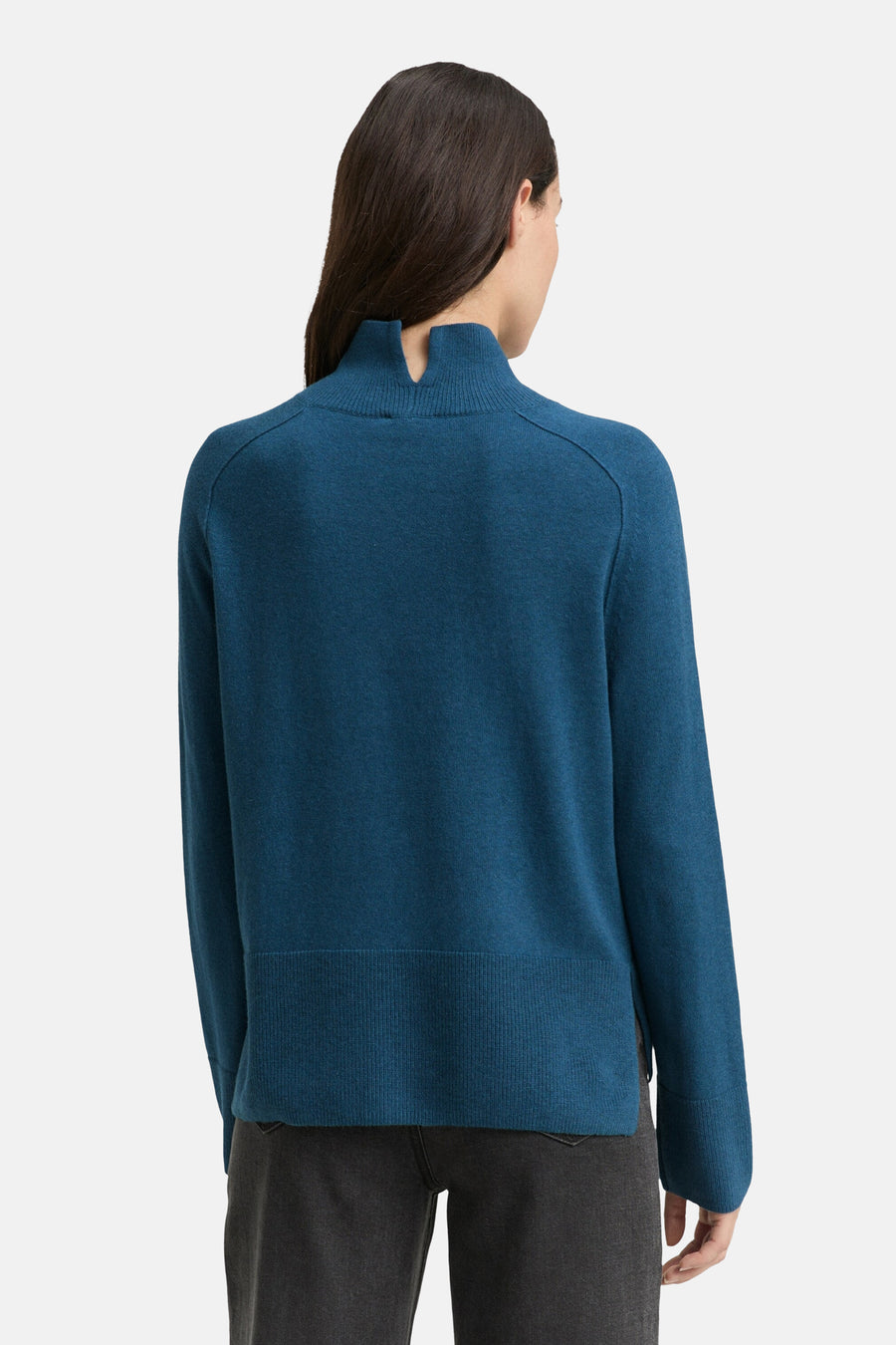 Blauwe coltrui van Tom Tailor, met uitgesneden col aan de achterkant, gedragen met een donkergrijze broek.