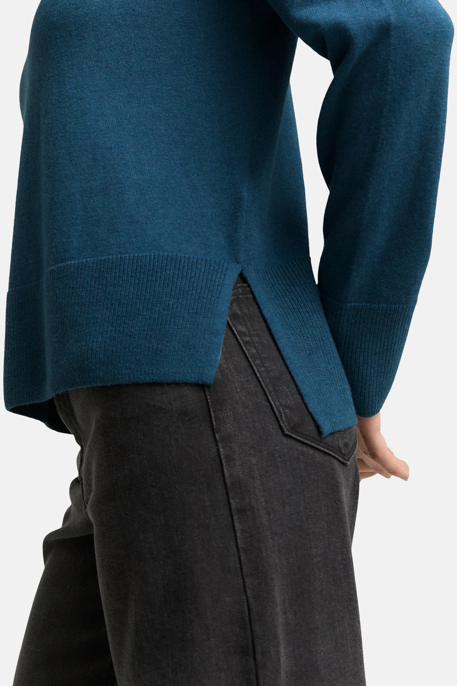 Blauwe coltrui van Tom Tailor, met geribde zoom en zijsplitten, gedragen met een zwarte jeans.