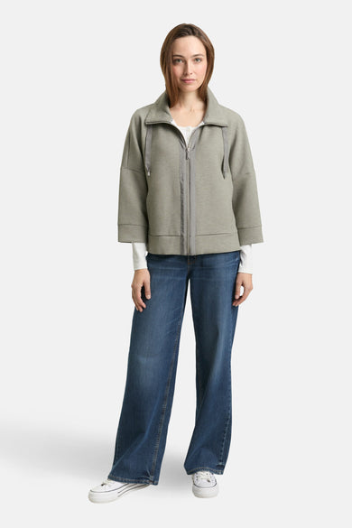 Cardigan kaki de Tom Tailor avec fermeture éclair et manches courtes amples porté avec un jean et des baskets blanches.