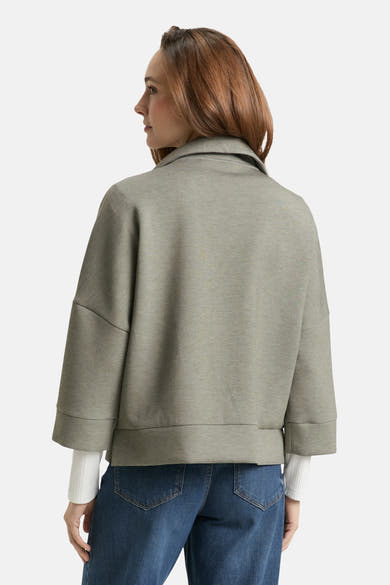 Cardigan kaki de Tom Tailor, avec des manches trois-quarts et porté avec un jean bleu.
