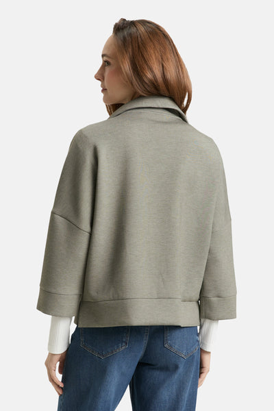Cardigan kaki de Tom Tailor, avec des manches trois-quarts et porté avec un jean bleu.
