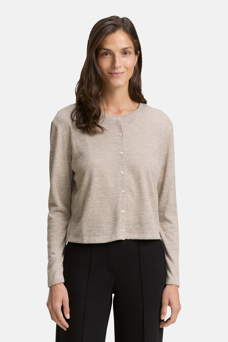 Beige vest van Tom Tailor, gebreid met knopen, gedragen met een zwarte broek.