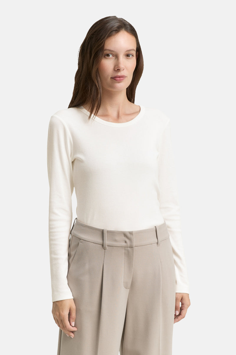 Witte T-shirt met lange mouwen van Tom Tailor, gedragen met een beige pantalon.