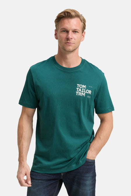 Groen T-shirt met korte mouwen van Tom Tailor, gedragen met een spijkerbroek, man met een hand in zijn zak.