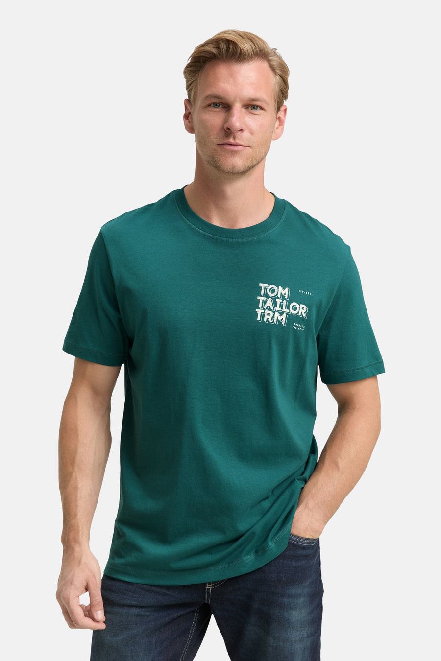 Groen T-shirt met korte mouwen van Tom Tailor, gedragen met een spijkerbroek, man met een hand in zijn zak.