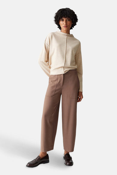 Pull à col rond beige d'OPUS, porté avec un pantalon marron taille haute et des mocassins noirs.
