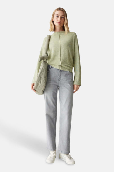 Pull à col rond vert de OPUS, porté avec un jean gris et un sac matelassé.