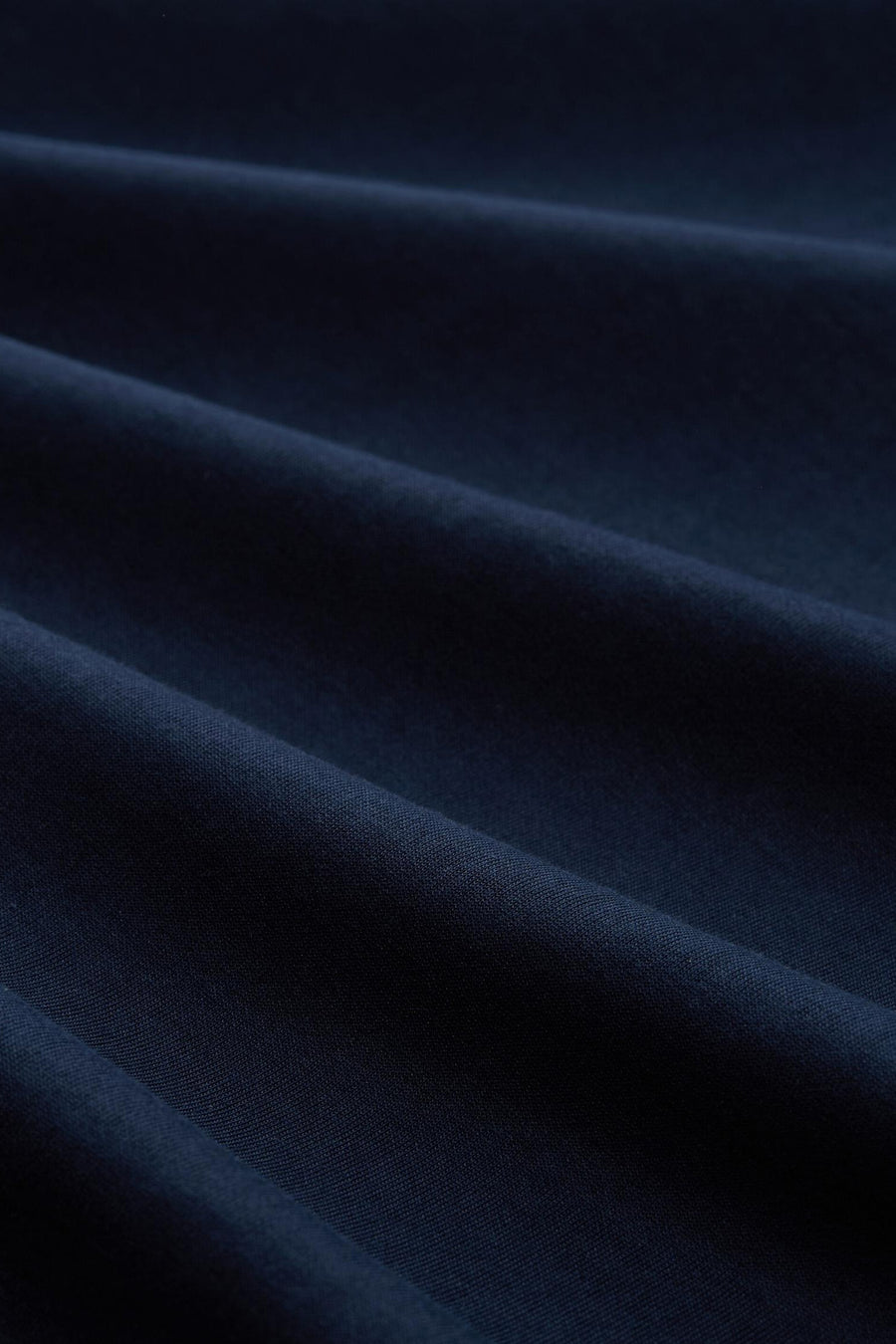 Donkerblauwe jas van Tom Tailor, getextureerde stof met zachte plooien en subtiele glans.