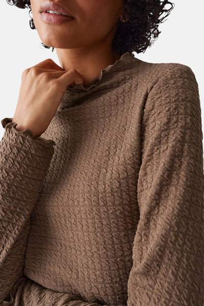 T-shirt à manches longues marron, de OPUS, avec texture gaufrée et col montant volanté, porté avec des boucles d'oreilles pendantes.