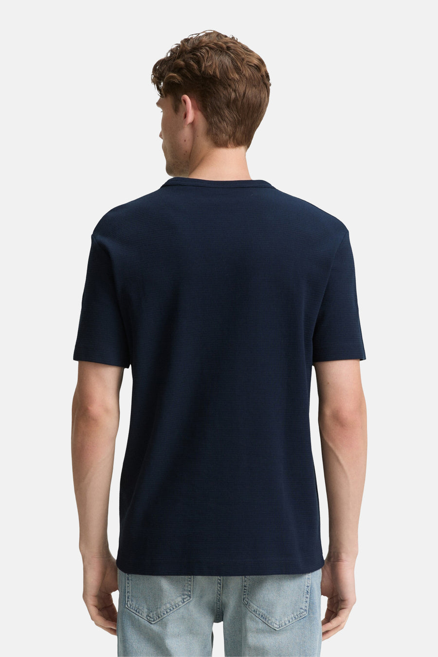 Blauw T-shirt met korte mouwen van Tom Tailor, van achteren gezien, gedragen met een spijkerbroek.