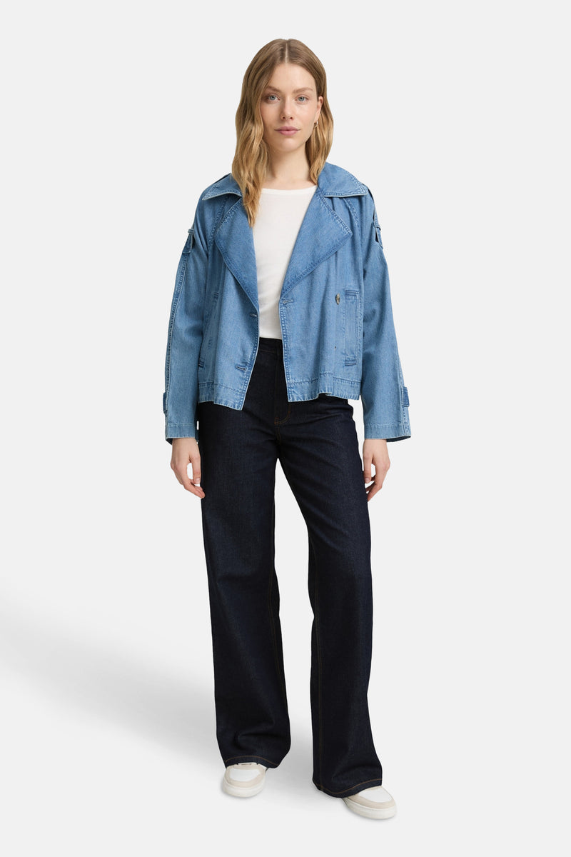 Wijde donkerblauwe spijkerbroek van Tom Tailor, gedragen met een kort jasje en witte sneakers.