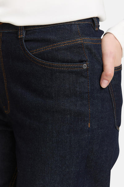 Wijde donkerblauwe spijkerbroek van Tom Tailor met bruine stiksels en een hand in de zak.