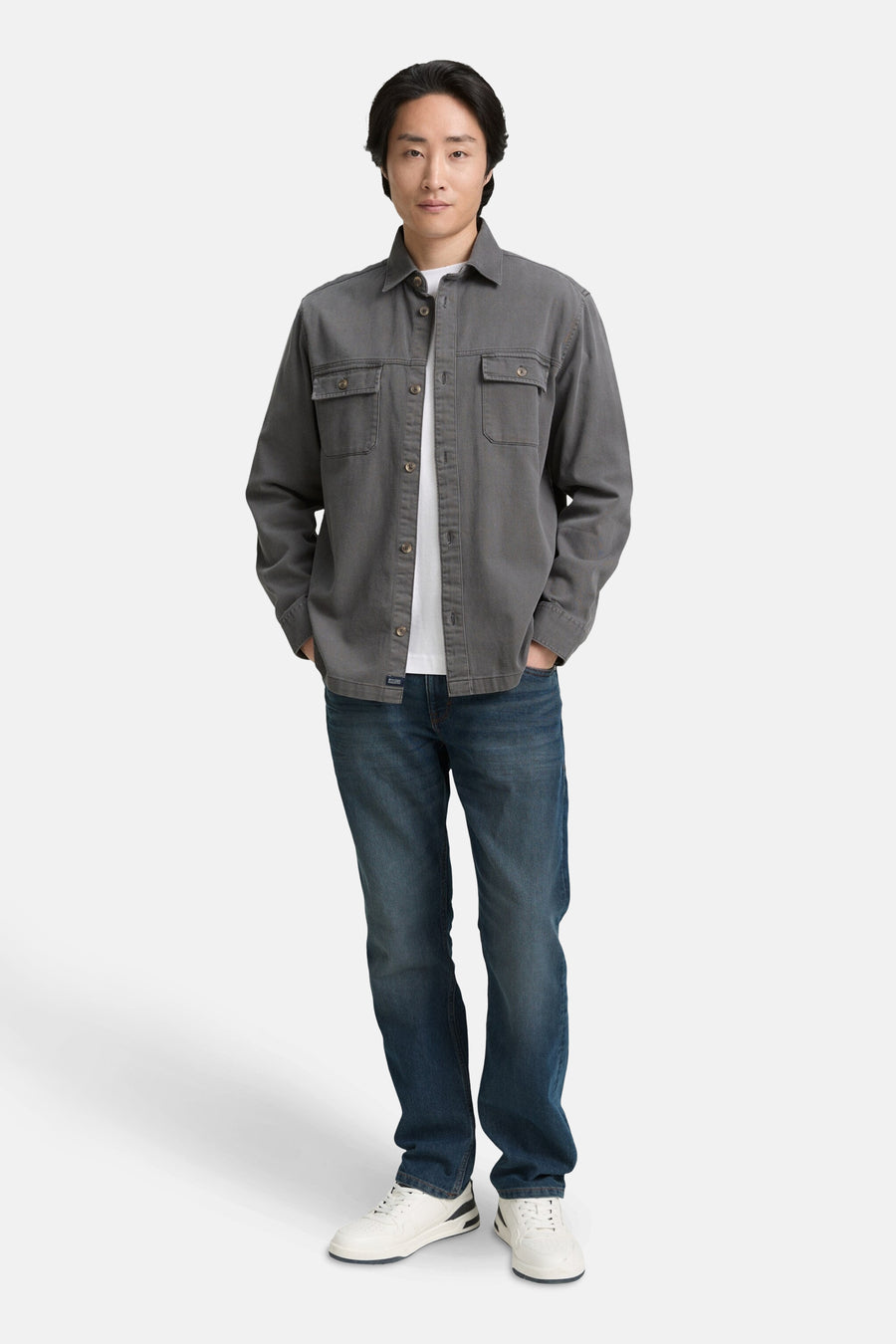 Rechte blauwe denim jeans van Tom Tailor, gedragen met een grijs overhemd en witte sneakers.