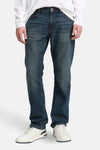 Rechte spijkerbroek in middinblauw denim van Tom Tailor, gedragen met een wit T-shirt en witte sneakers.