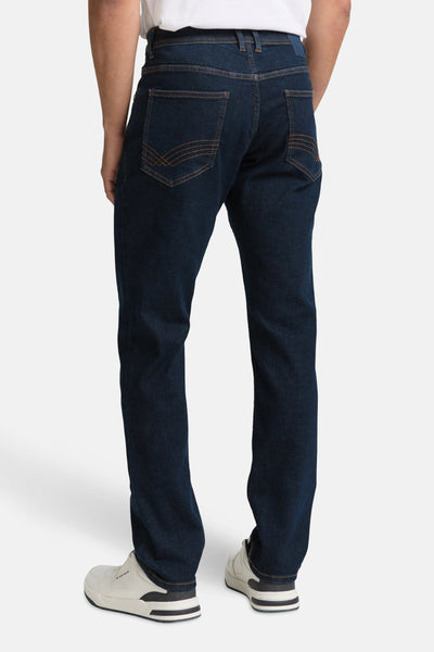 Slim jeans in donkerblauw denim van Tom Tailor, met sierlijke achterzakken en omgeslagen zoom op witte sneakers.