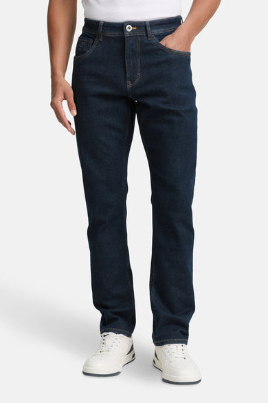 Tom Tailor donkerblauwe denim slim fit jeans, met zakken en witte schoenen.