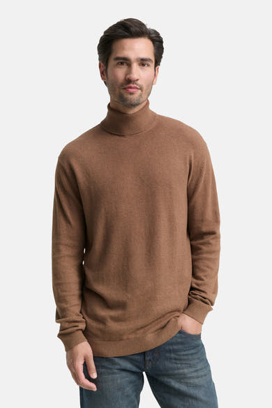 Bruine coltrui van Tom Tailor, gedragen met een blauwe spijkerbroek, op een witte achtergrond.
