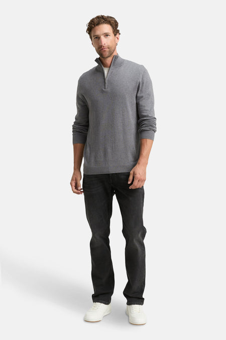 Pull col roulé gris de Tom Tailor, porté avec un t-shirt blanc, un jean noir et des baskets blanches.