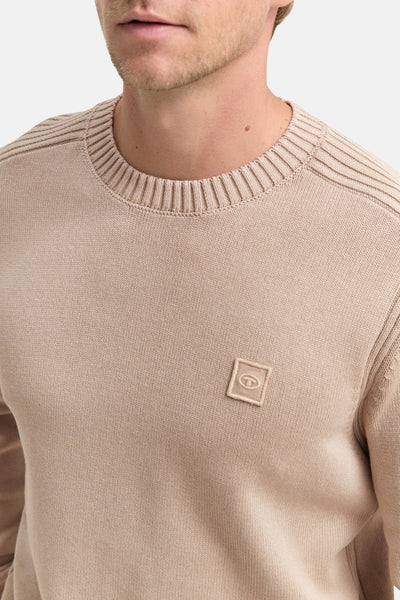 Pull à col rond beige de Tom Tailor, avec détails côtelés à l'encolure et patch discret sur la poitrine.