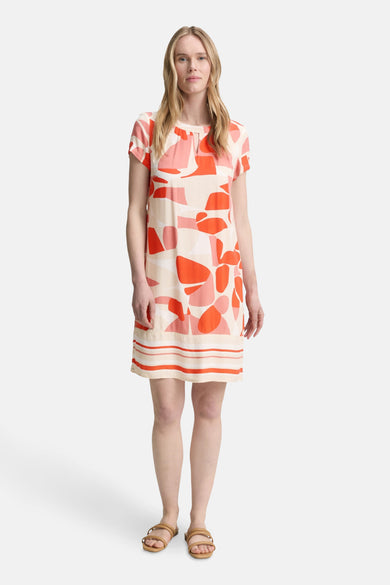 Robe courte orange à motifs géométriques de Tom Tailor, avec rayures horizontales à l'ourlet et des sandales portées par le modèle.
