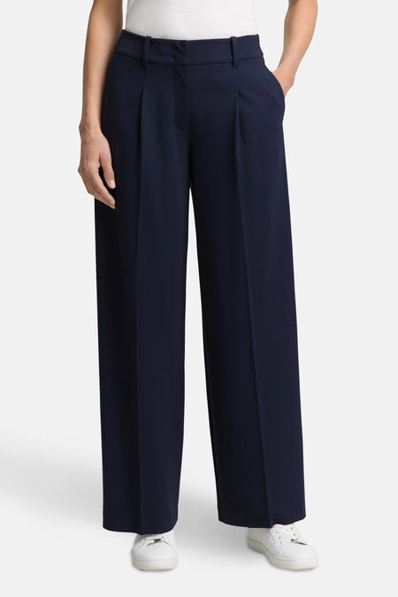 Blauwe Tom Tailor pantalon, wijde pasvorm met plooien en zijzakken, gedragen met witte sneakers.