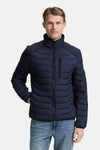 Veste courte bleue par Tom Tailor, matelassée à chevrons avec empiècements texturés aux épaules, portée avec un jean décontracté.