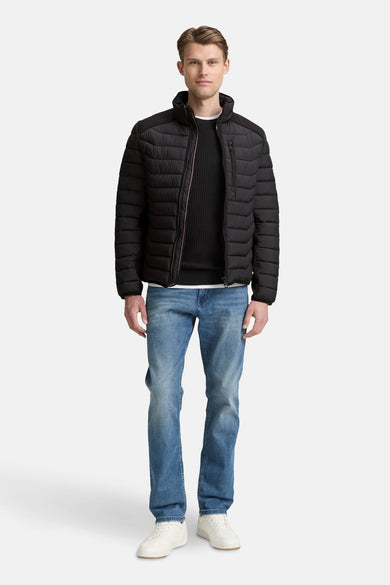 Veste courte noire de Tom Tailor, portée avec un pull noir, un jean bleu et des baskets blanches.