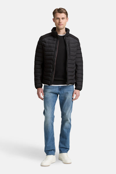 Veste courte noire de Tom Tailor, portée avec un pull noir, un jean bleu et des baskets blanches.