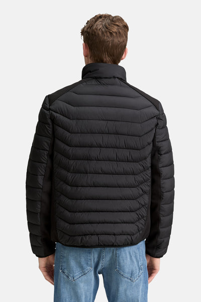Veste courte noire Tom Tailor, matelassée avec un motif horizontal, portée avec un jean.