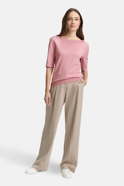 Roze T-shirt met korte mouwen van Tom Tailor, gedragen met een beige geplooide broek en witte sneakers.