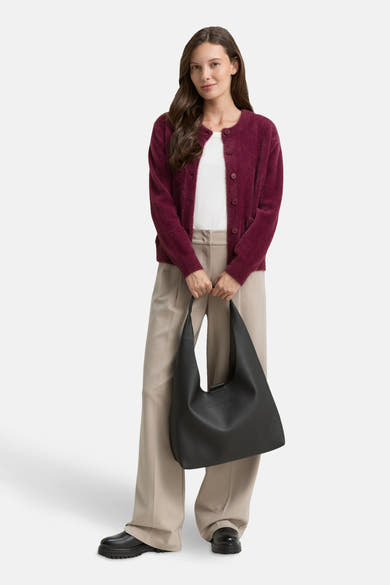 Rode, pluizige gebreide cardigan van Tom Tailor, gedragen met een wijde beige broek en een zwarte tas.